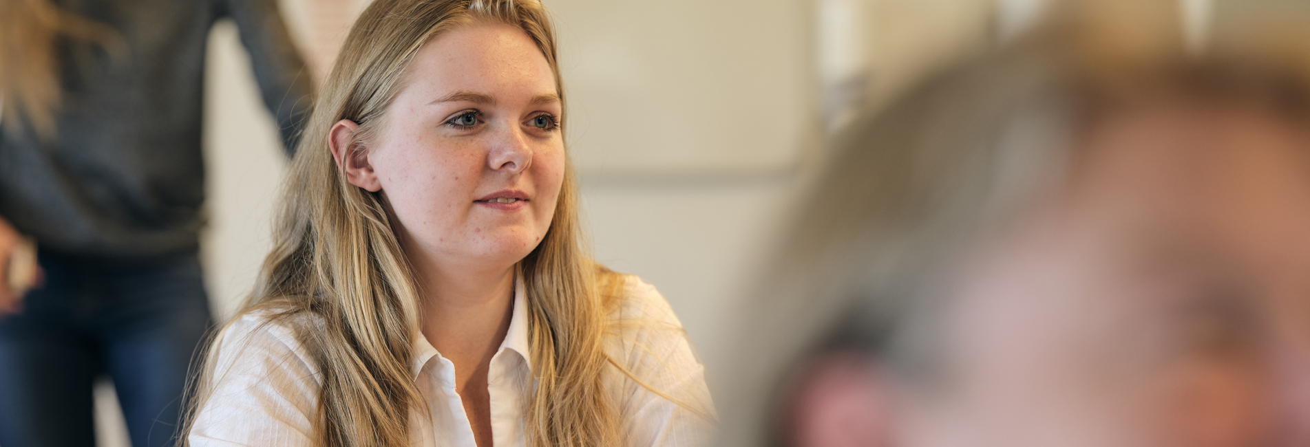 Kvinde som sidder i natuen og ser på sin laptop. 